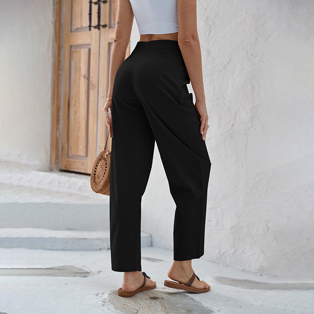 Woman wearing high-waisted wide-leg pants with a knot detail and a tucked-in top.