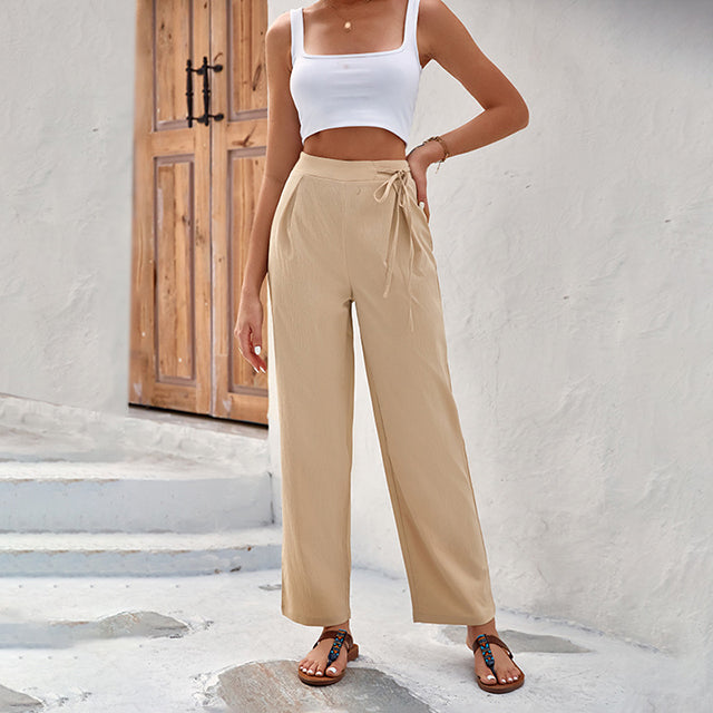 Woman wearing high-waisted wide-leg pants with a knot detail and a tucked-in top.