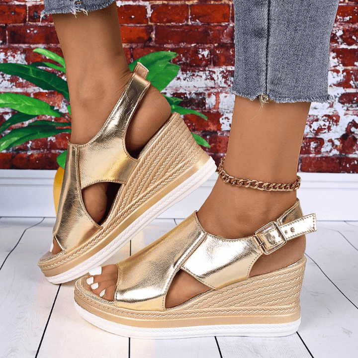 A woman wearing gold metallic sandals with a cushioned insole and wide, supportive fit.