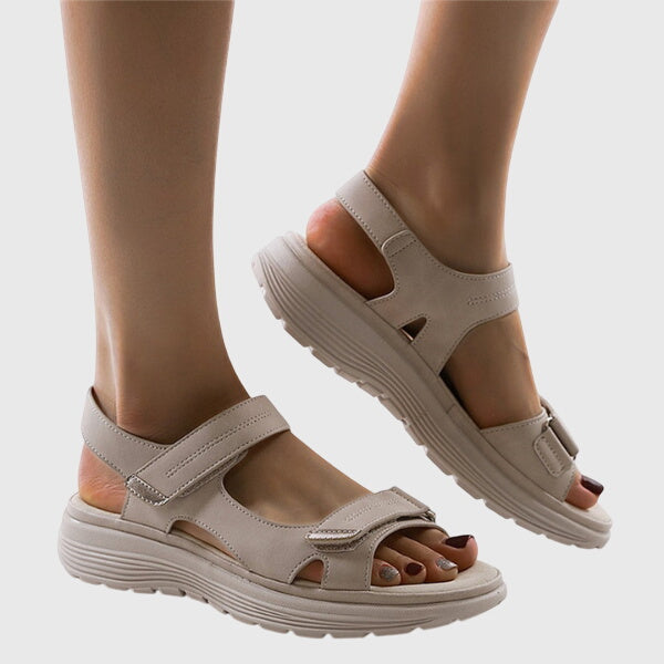 A woman in beige adjustable strap sandals standing steady and relaxed on a sunny path.