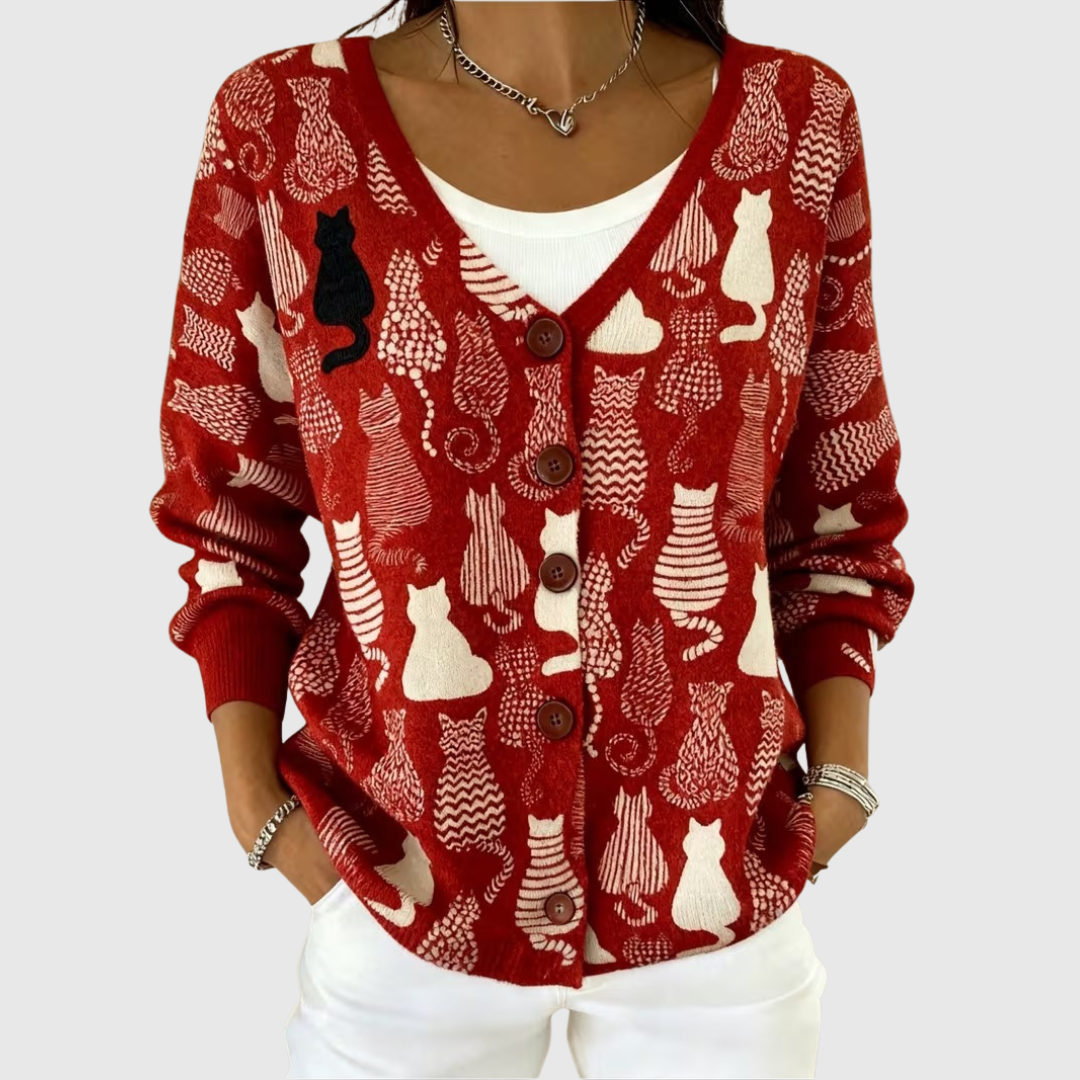 A woman wearing a red buttoned cardigan patterned with cream cats and one black cat.