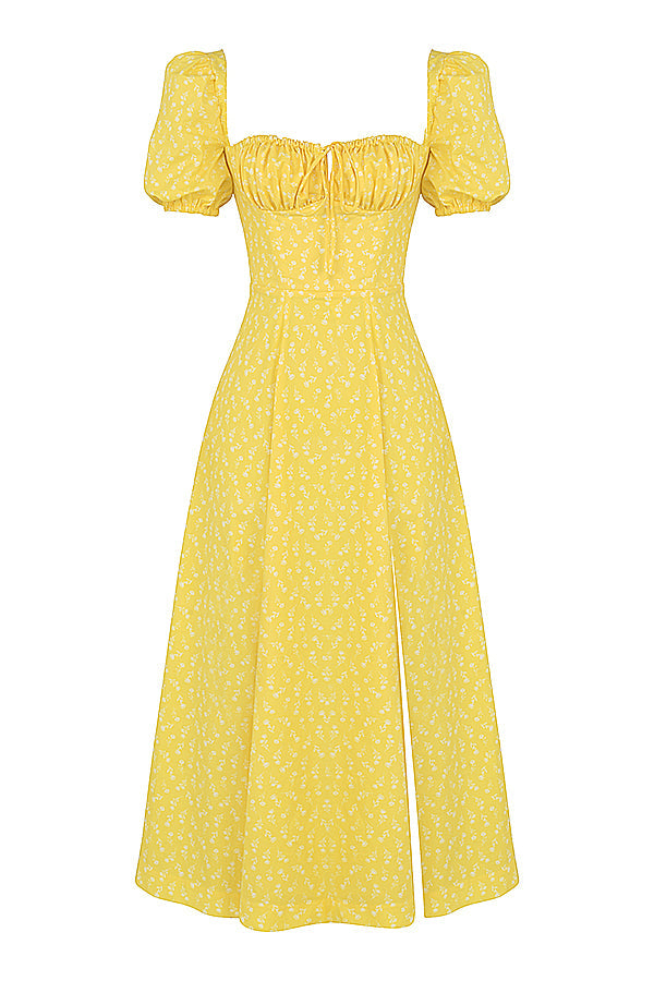 A woman wearing a floral midi dress with puff sleeves and a tie-front bodice, standing in the sunshine.