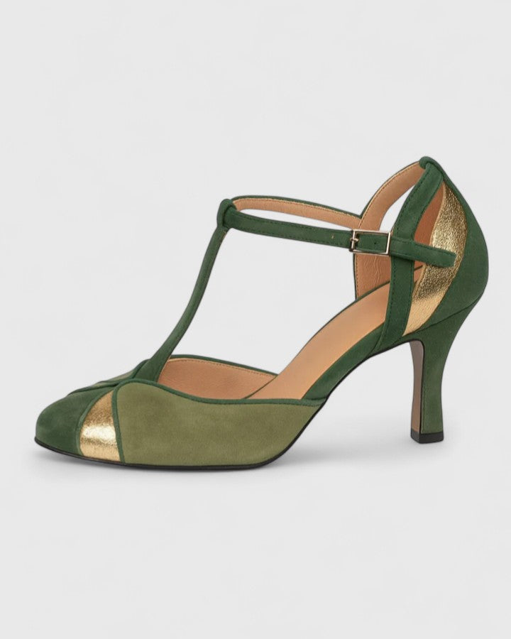 A woman wearing green T-strap heels with a rounded toe and gold trim, stepping out in a bright, elegant look.