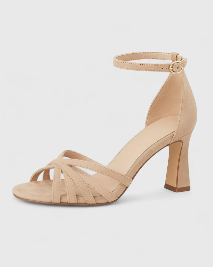 A woman in beige open-toe block heels with an ankle strap at a summer occasion.