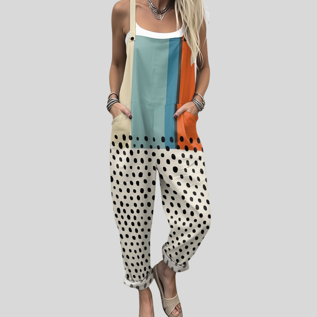 A woman wearing colour-block overalls with teal and orange blocks and black spots on cream, with adjustable straps.