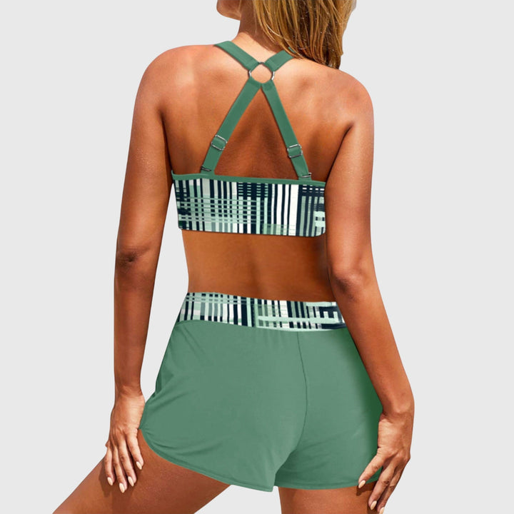 A woman at the beach in a striped bikini top with matching swim shorts, confident and relaxed in the sun.