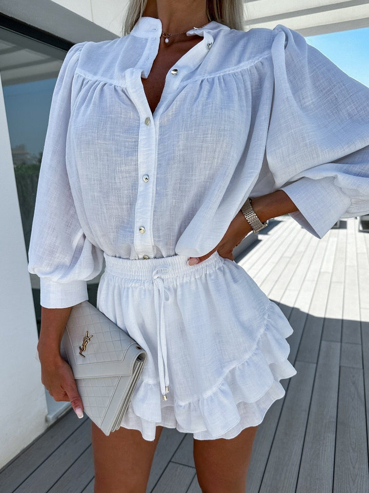 A woman wearing a white buttoned top with ruffled shorts