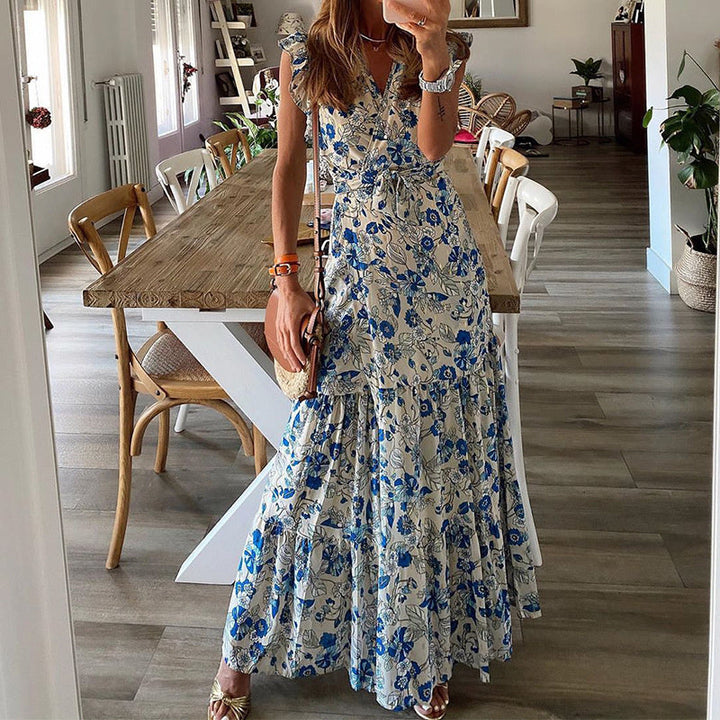 Woman in a flowing floral maxi dress with a tied waist at a summer garden gathering.