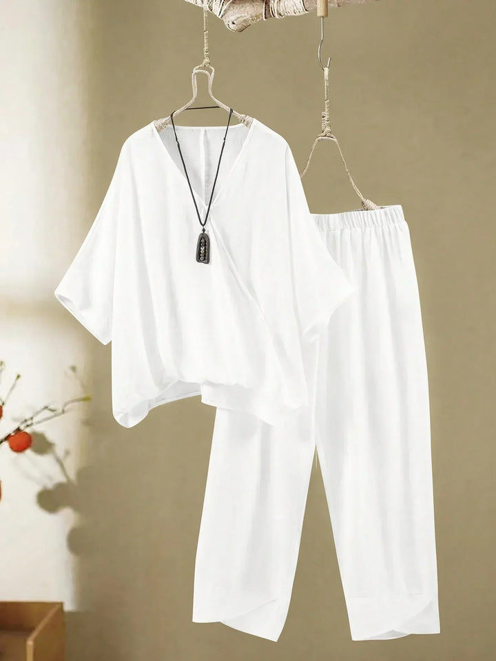 A woman wearing a flowing V-neck knot-detail top with matching flared pants.