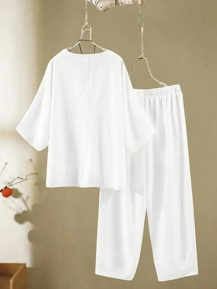 A woman wearing a flowing V-neck knot-detail top with matching flared pants.