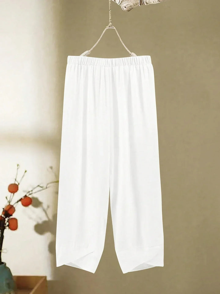 A woman wearing a flowing V-neck knot-detail top with matching flared pants.
