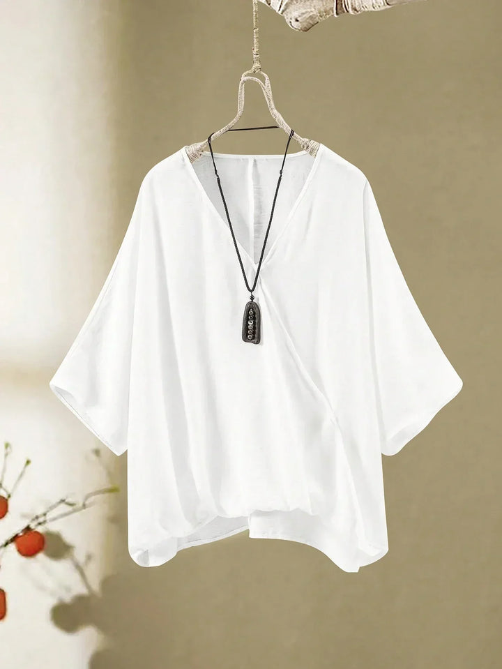 A woman wearing a flowing V-neck knot-detail top with matching flared pants.