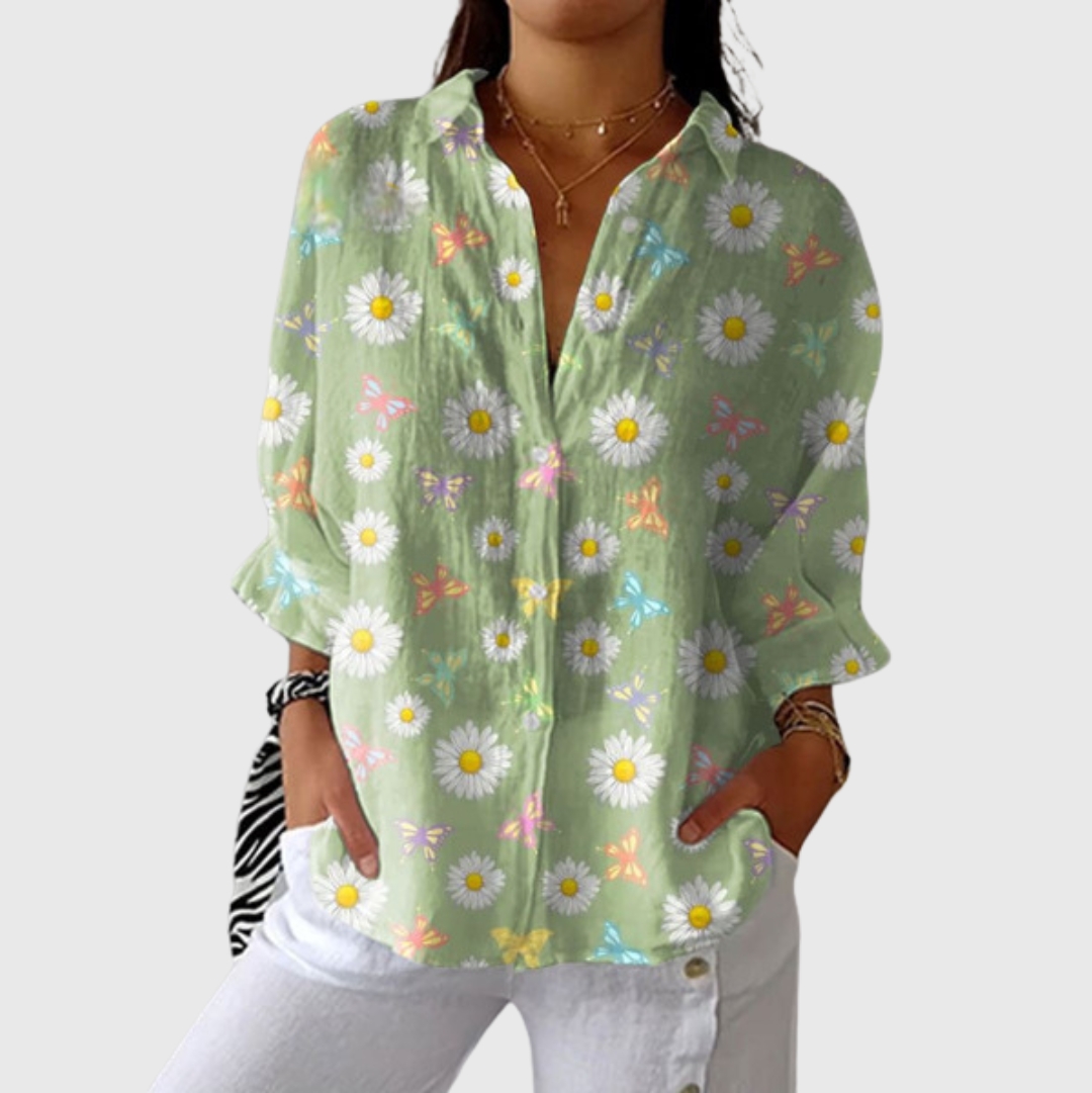 A woman in a bright floral blouse worn loose, smiling in the sunshine