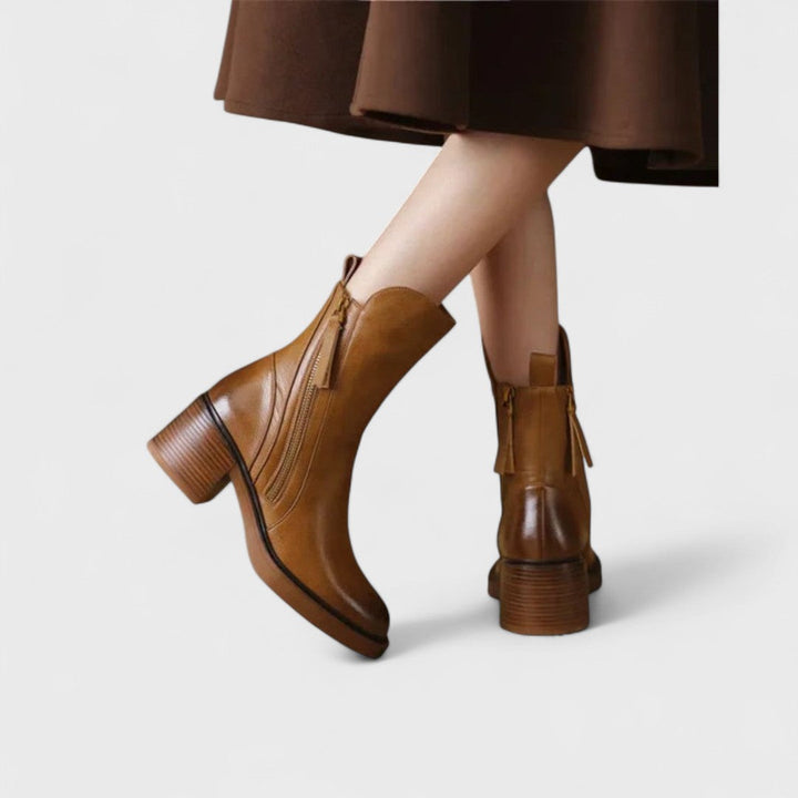 Woman wearing black refined ankle boots with tailored pants in a city setting.