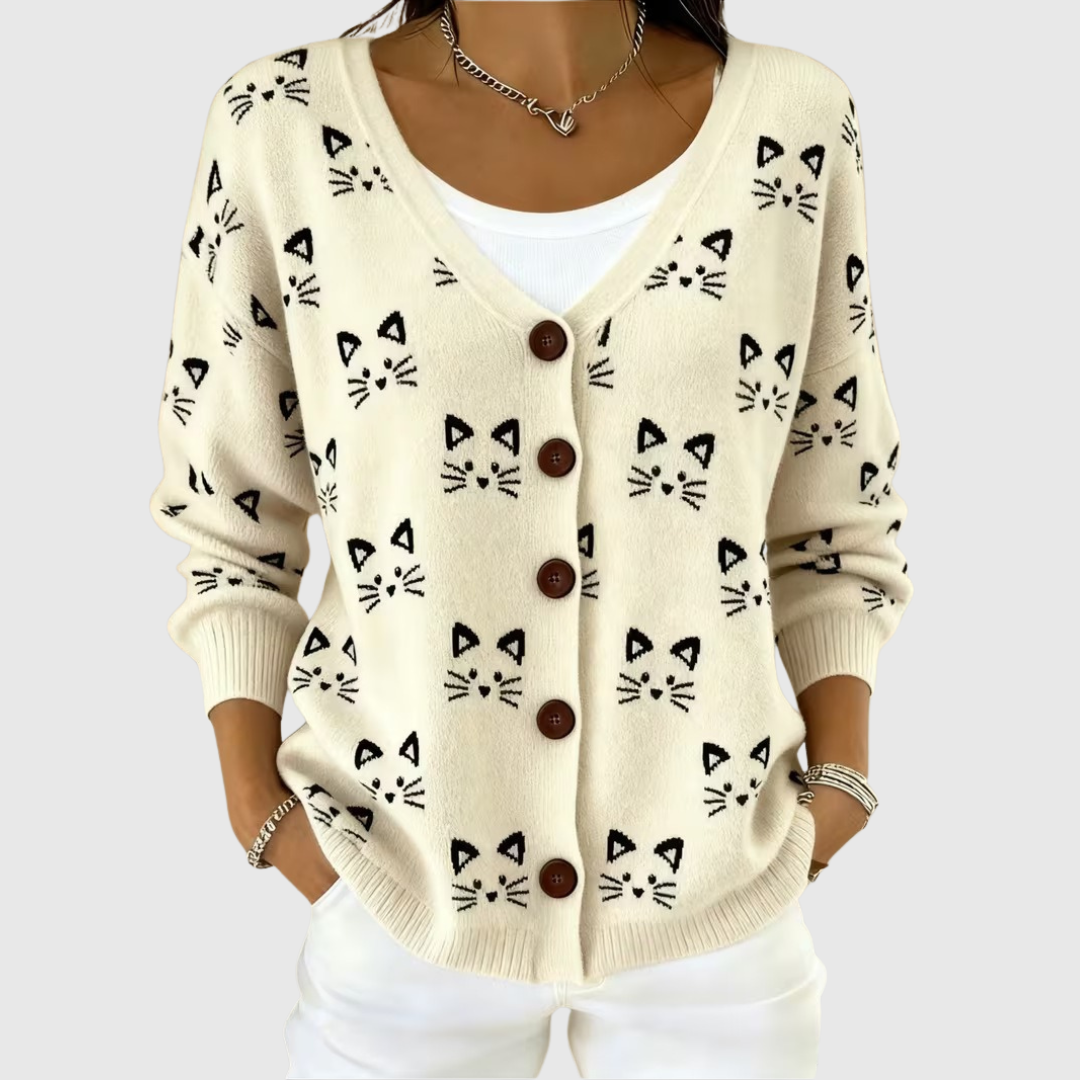 A woman wearing a cream button cardigan with a black cat face print over a white top.