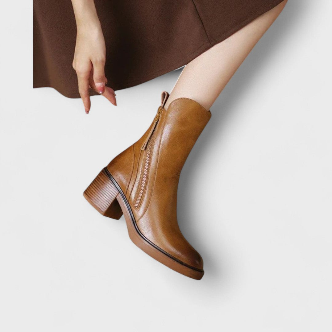 Woman wearing black refined ankle boots with tailored pants in a city setting.