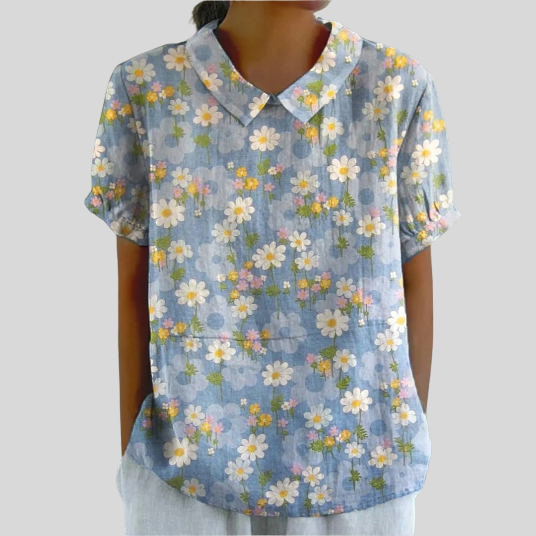 A woman wearing a blossom-print top with a polo collar that drapes softly over her figure.