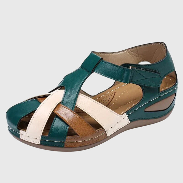 A woman wearing burgundy and brown woven closed-toe wedge sandals with side cutouts, walking with ease