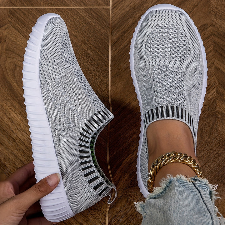 A woman slipping on ultralight sock-style sneakers that hug the foot.