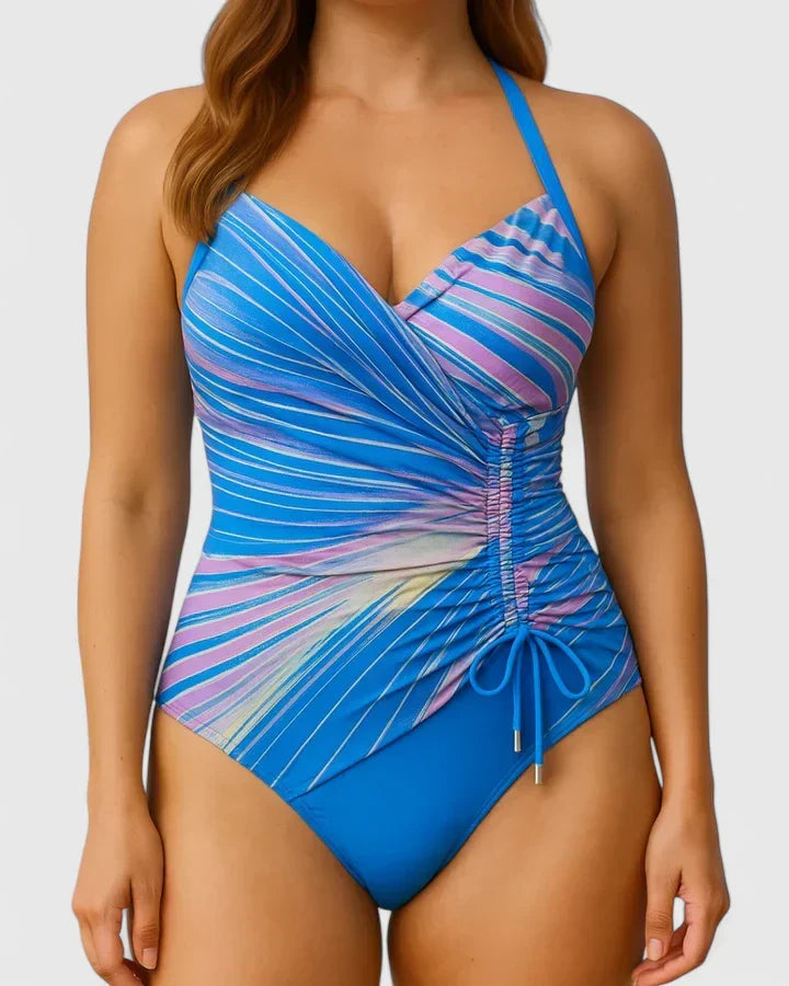 A woman in a navy and white striped wrap swimsuit, relaxed and elegant in the summer sun.