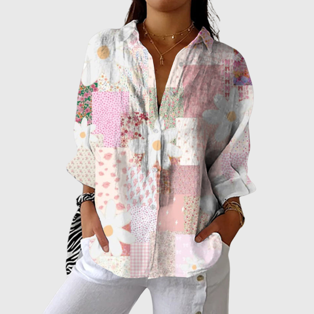 A woman in a colourful floral printed blouse worn loose, smiling in the sun