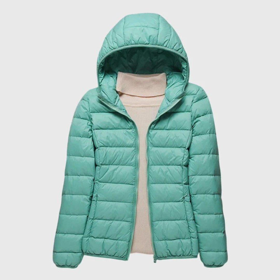 A woman wearing a lightweight padded jacket with a hood, outdoors on a cool day