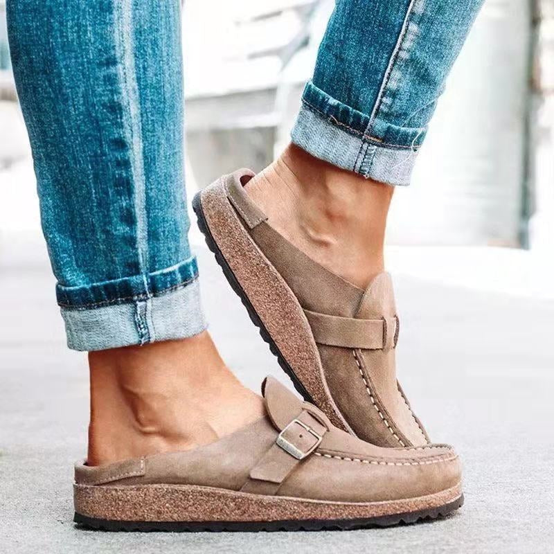 A woman wearing soft taupe buckle clog mules with cropped jeans on a city stroll.