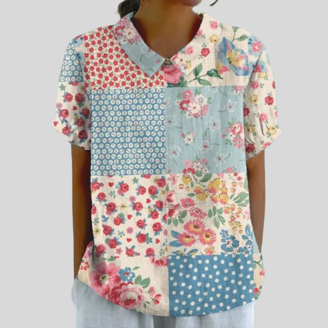 A woman wearing a patchwork-print top blending florals and polka dots, finished with a chic collar, at ease at a relaxed garden gathering.