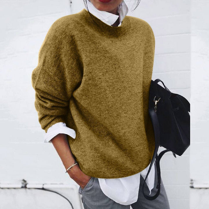 A woman wearing a soft mustard round-neck sweater with an elegant modern shape, relaxed and warm.