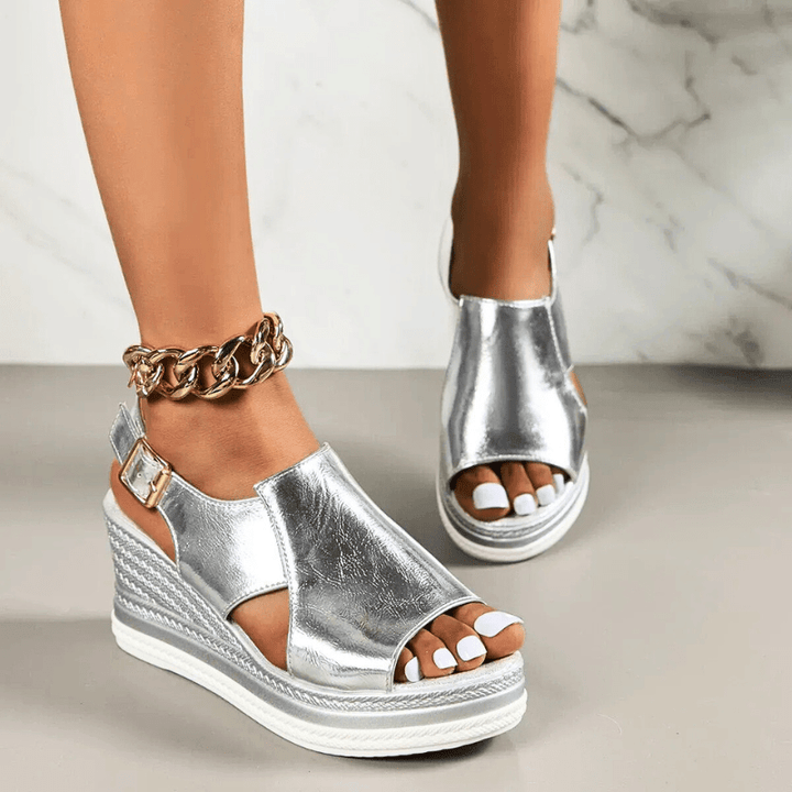A woman wearing gold metallic sandals with a cushioned insole and wide, supportive fit.