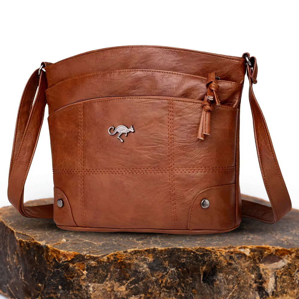 A woman wearing a brown cross-body bag across her body while out in the city