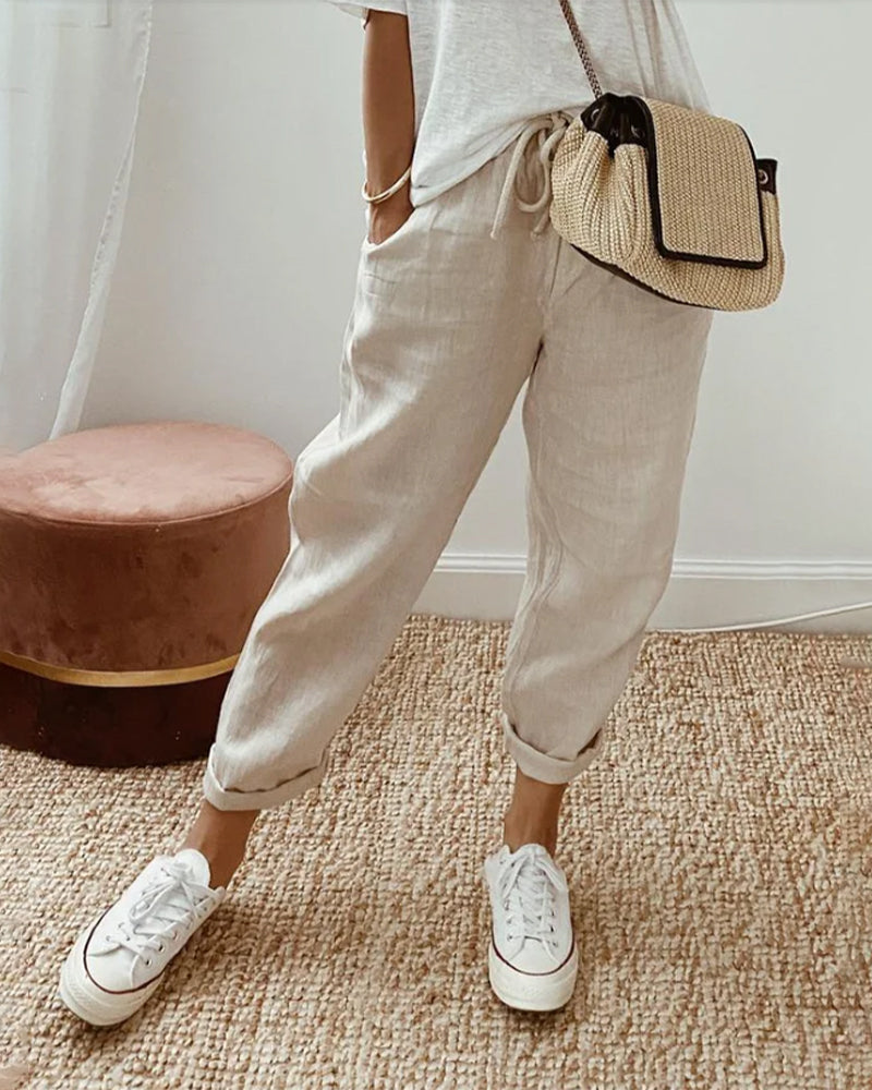 A woman wearing flowing elegant pants with a soft elastic waist and deep pockets.