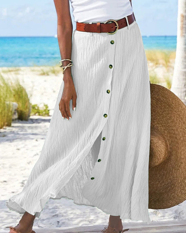 Woman wearing a flowing high-waisted button skirt with a tucked-in top, walking outdoors.