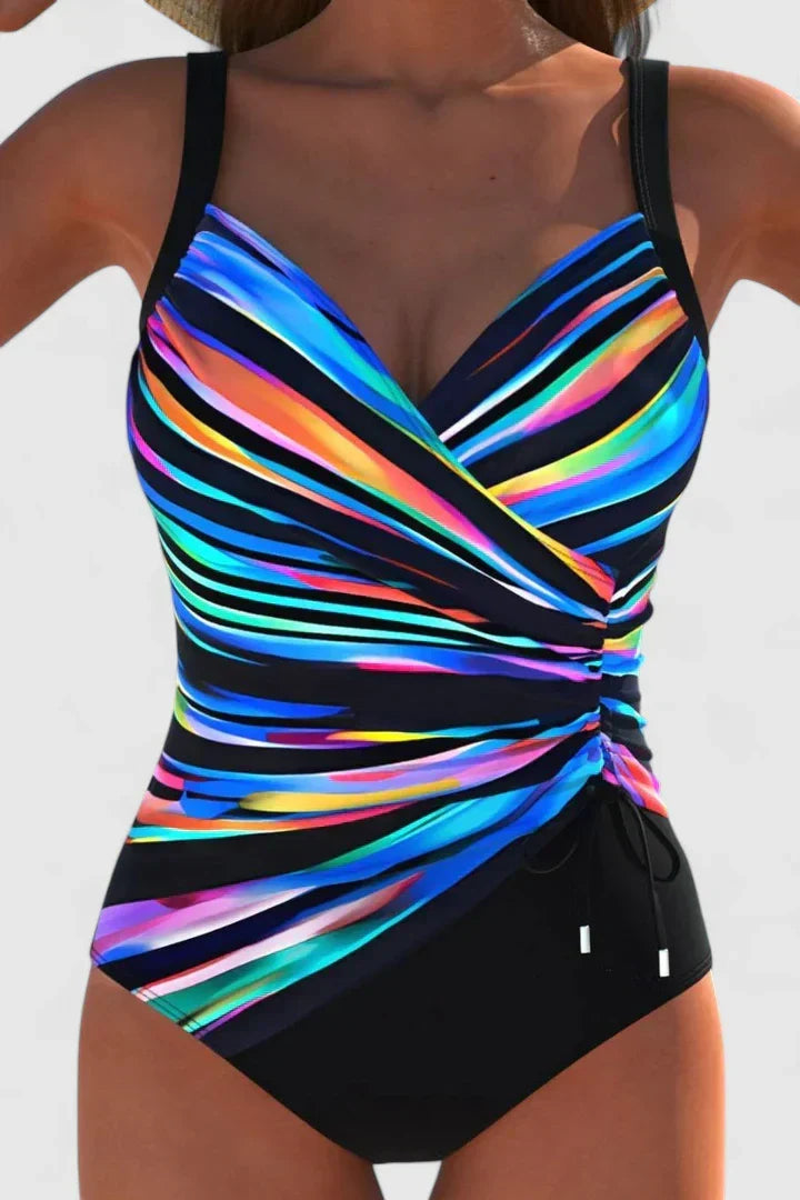 A woman in a navy and white striped wrap swimsuit, relaxed and elegant in the summer sun.