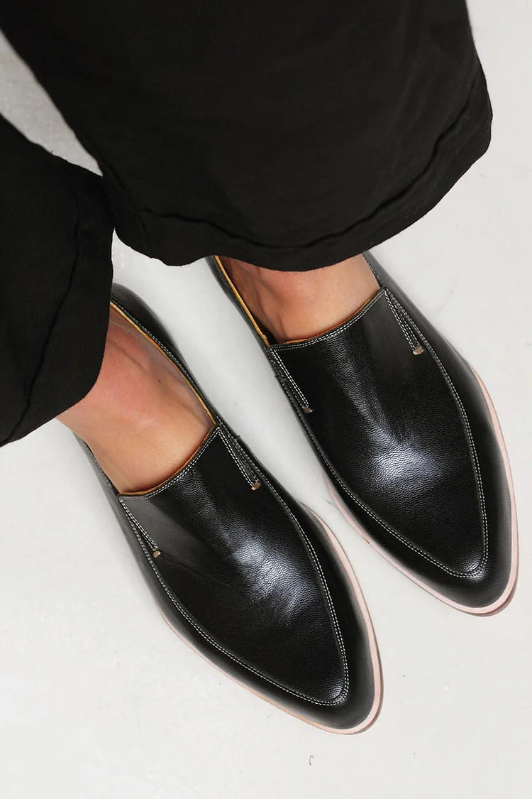 A woman wearing black patchwork slip-on loafers, styled for an easy day in the city.