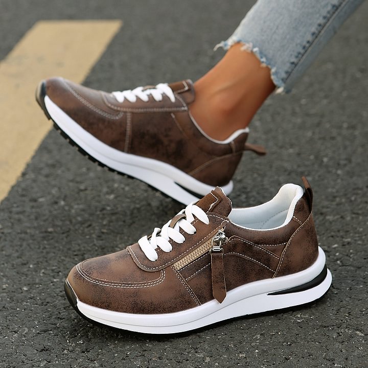 A woman wearing cushioned orthopaedic sneakers with a side zip
