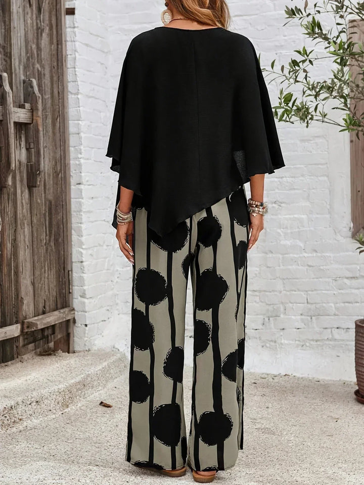 A woman wearing a draped asymmetric top with printed high-waisted wide-leg pants.