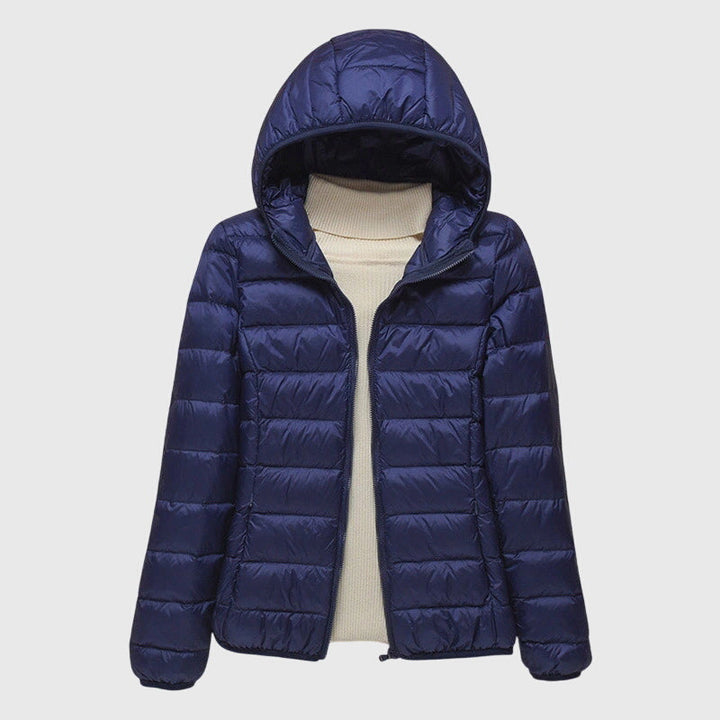 A woman wearing a lightweight padded jacket with a hood, outdoors on a cool day