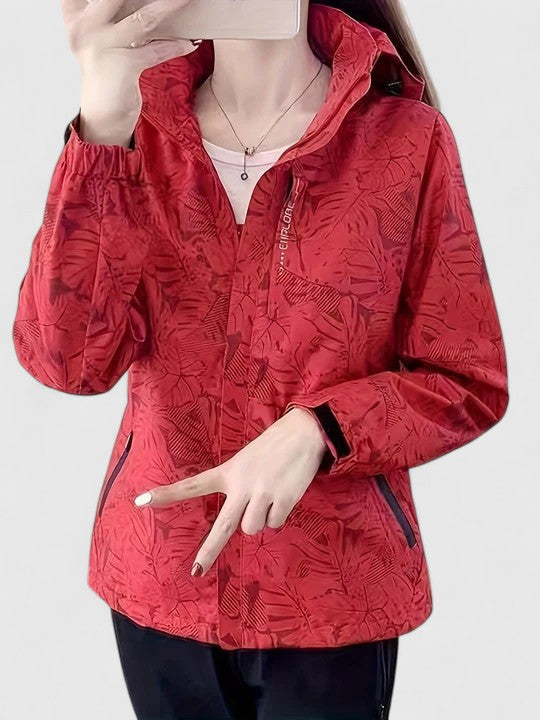 A woman wearing a botanical leaf-print jacket with a hood outdoors