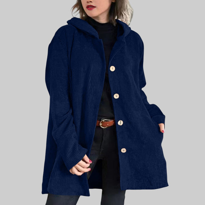 A woman wearing a hooded textured jacket outdoors in fall