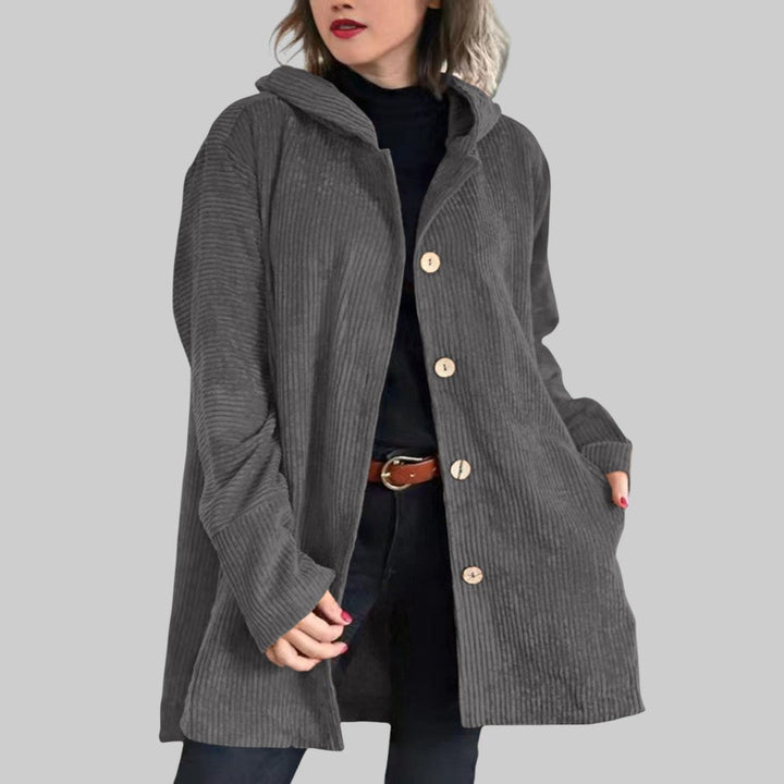 A woman wearing a hooded textured jacket outdoors in fall
