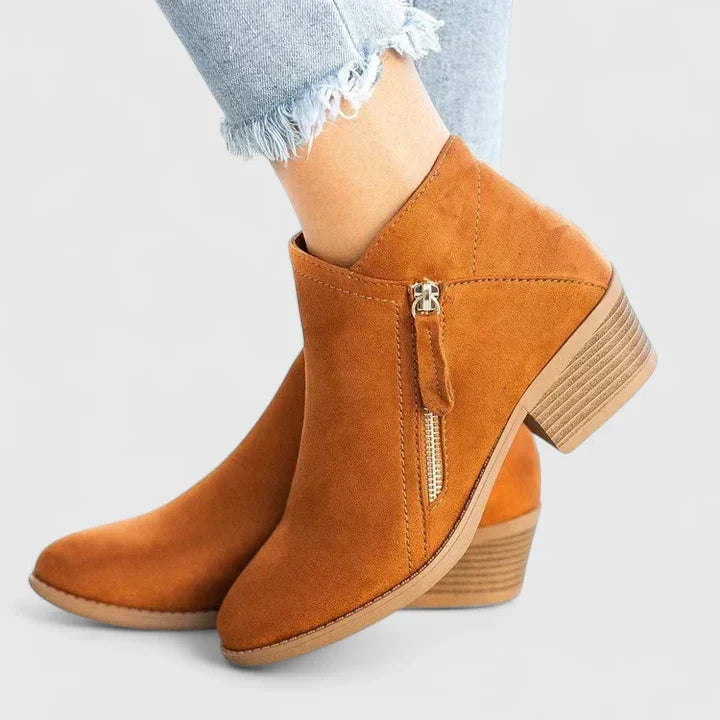 Woman wearing black side-zip ankle boots, stepping off a kerb in town.