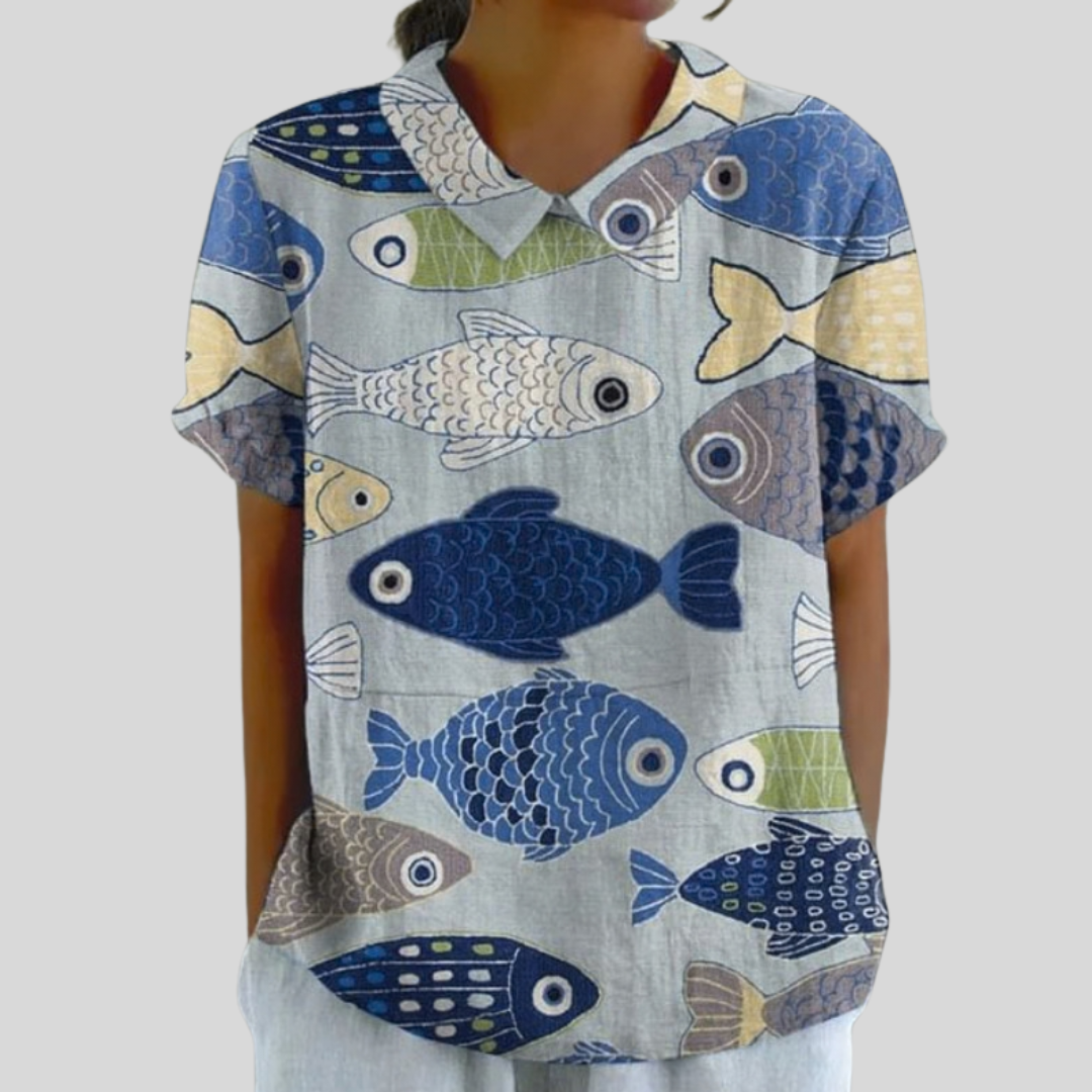 A woman wearing a blue and grey fish print top with a polo collar on a relaxed day