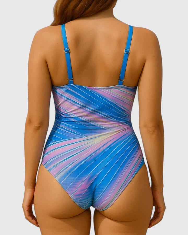 A woman in a navy and white striped wrap swimsuit, relaxed and elegant in the summer sun.