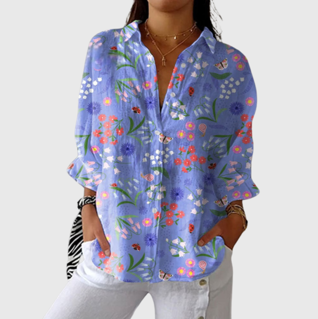 A woman wearing a relaxed colourful printed blouse with an elegant button front, styled with pants for a comfortable day out.