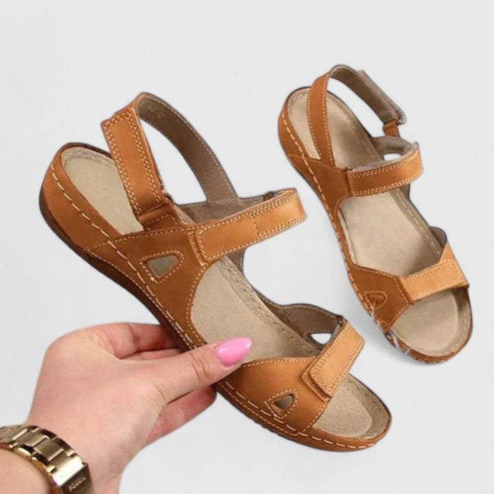 A woman walking through town in tan flat comfort sandals, relaxed and at ease.
