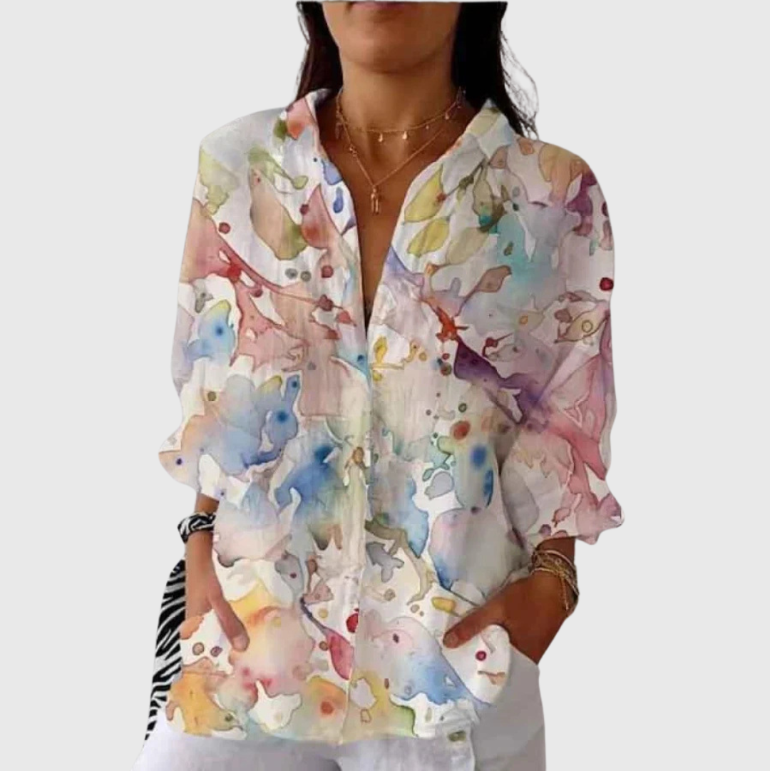 A woman wearing a loose colourful printed blouse with adjustable sleeves, styled with jeans for a bright day out.