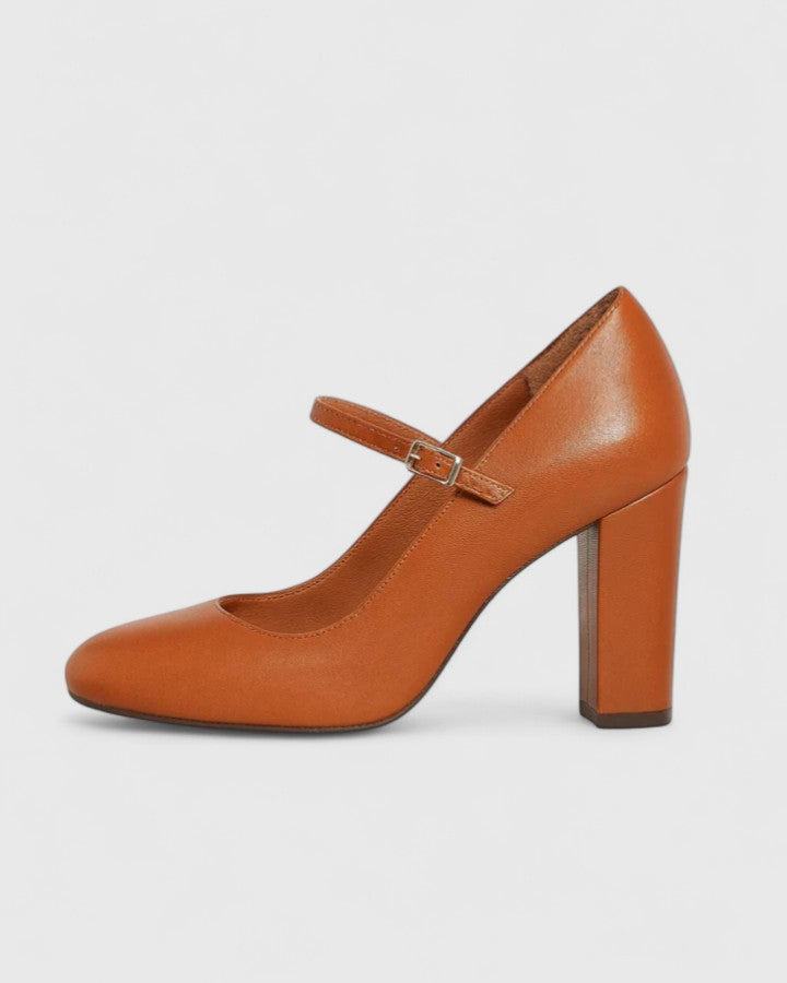 A woman wearing brown block heels with an ankle strap, walking confidently through her day.