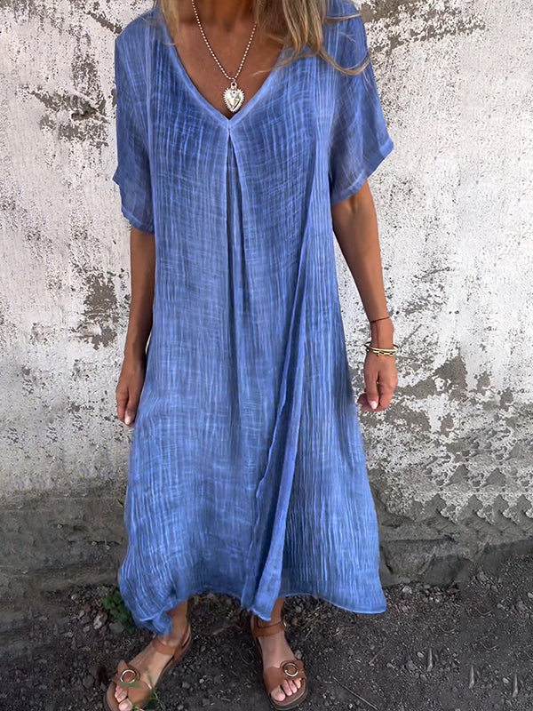 Woman wearing the Andrea™ flowing V-neck dress with short sleeves, standing relaxed in warm sunlight.