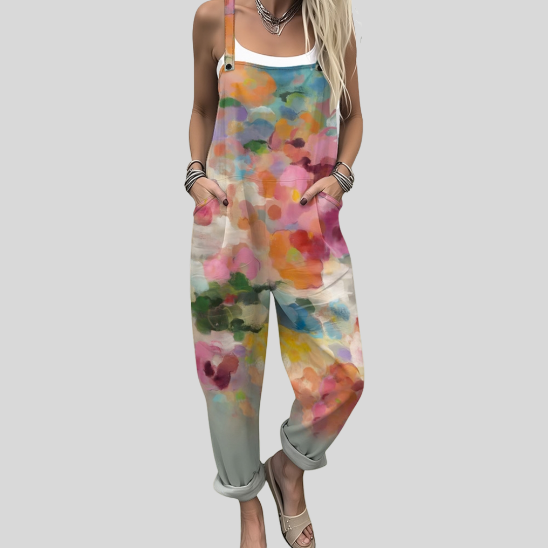 A woman wearing overalls with a dreamy watercolour floral print in pink, orange, turquoise and green.